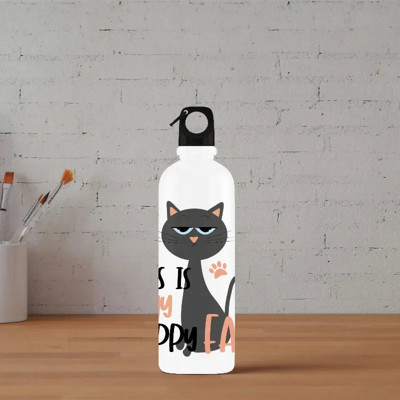 White water bottle with a black cat illustration and text on a wooden surface with a white brick wall background.