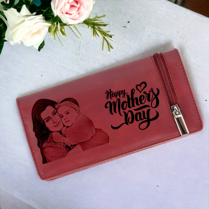 Red wallet with 'Happy Mother's Day' engraving and a portrait of a woman and child on a white surface with flowers.