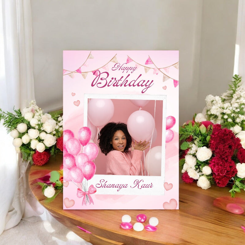 Happy Birthday card with balloons and flowers on a table