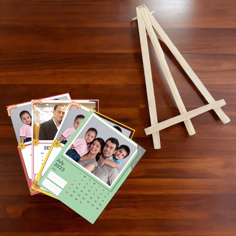 Personalized photo calendar with family portraits on a wooden surface with a small wooden easel.