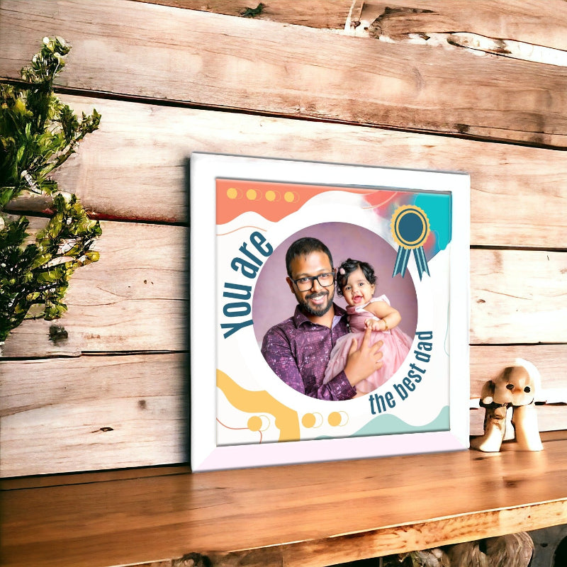 Framed picture of a father and child with decorative text on a wooden surface.