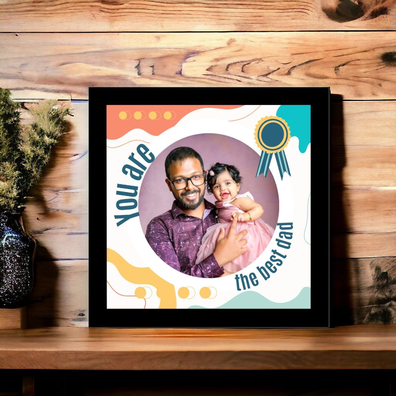 Framed photo of a man and a child with text 'You are the best dad' on a wooden surface.