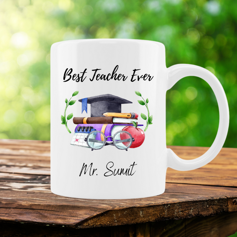 White mug with 'Best Teacher Ever' text and teacher-themed graphics on a wooden surface with a blurred green background