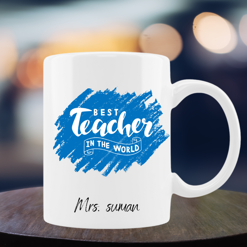 White mug with blue text 'Best Teacher in the World' and personalized name on a blurred background