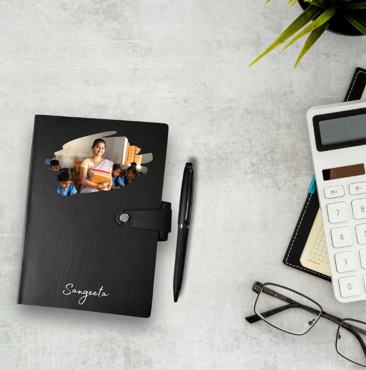 Black personalized notebook with a photo cover on a gray surface with a pen, glasses, and calculator.