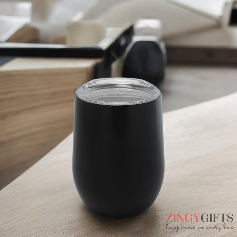 Black tumbler on a wooden surface with a blurred indoor background