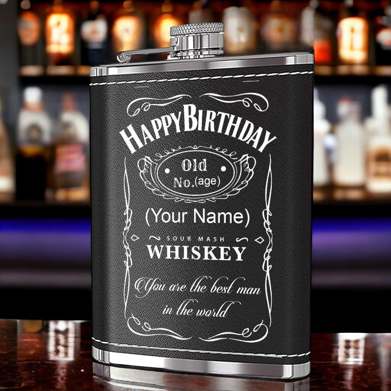 Personalized birthday whiskey flask with engraved text on a bar background