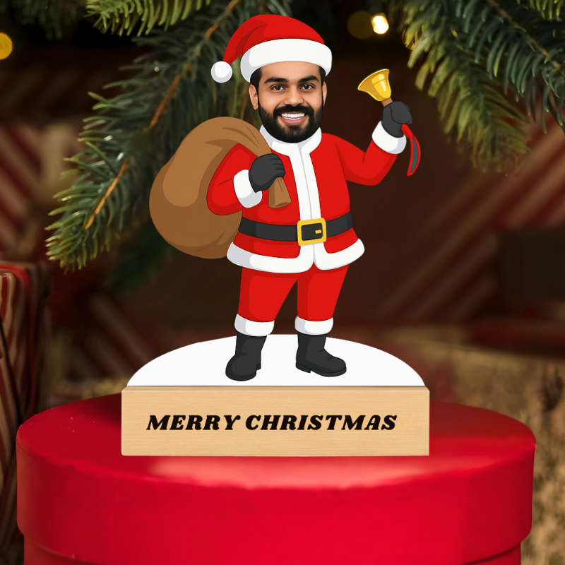 Santa Claus figurine with a 'Merry Christmas' sign on a red base, surrounded by Christmas tree branches.