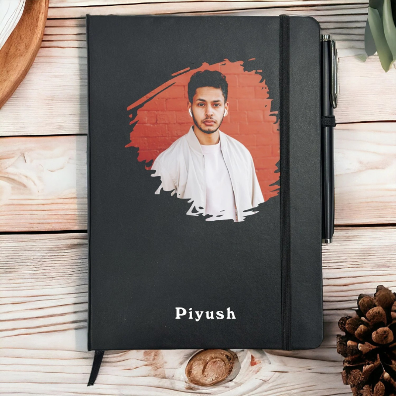 Black notebook with a portrait of a person on the cover, placed on a wooden surface.