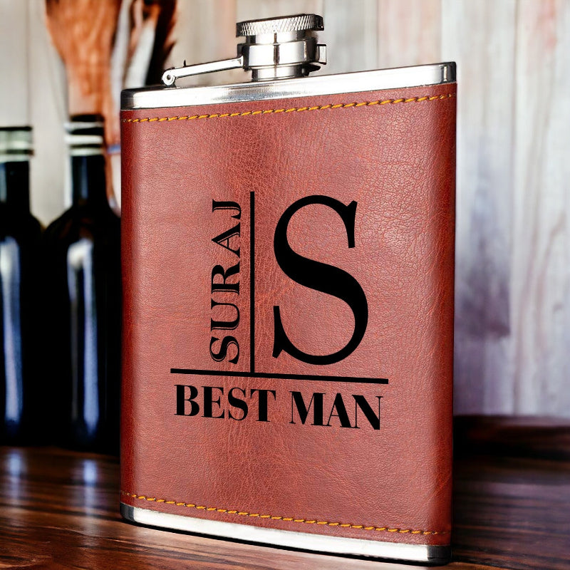 Brown leather flask with 'Suraj Best Man' engraving on a wooden surface.