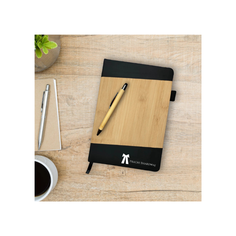 Wooden notebook with black cover on a wooden surface with a pen and coffee cup.