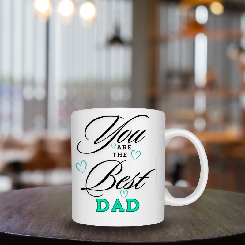 White mug with 'You are the best dad' text on a wooden table in a blurred cafe setting