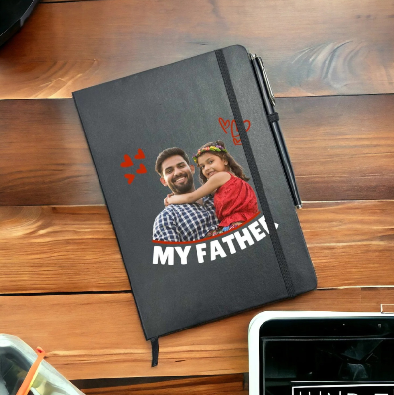 Black notebook with a photo of a man and a child on a wooden surface