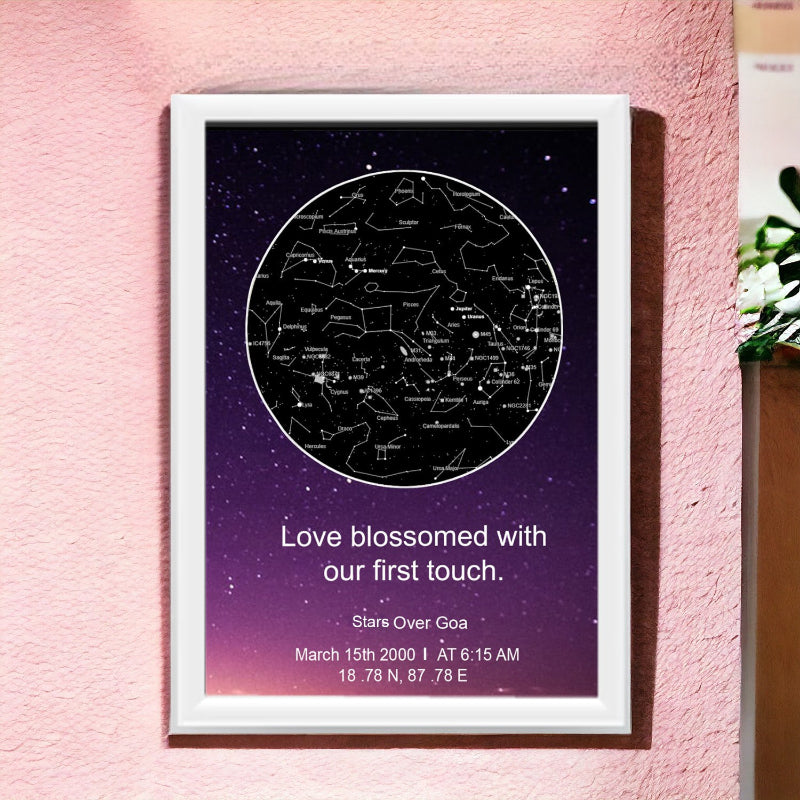A framed star map with white border hanging on a wall, featuring text personalization.