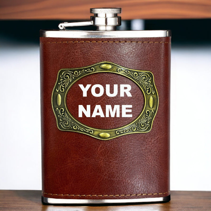 A brown leather hip flask with a metal cap and a personalized text 'YOUR NAME' embossed on the front.