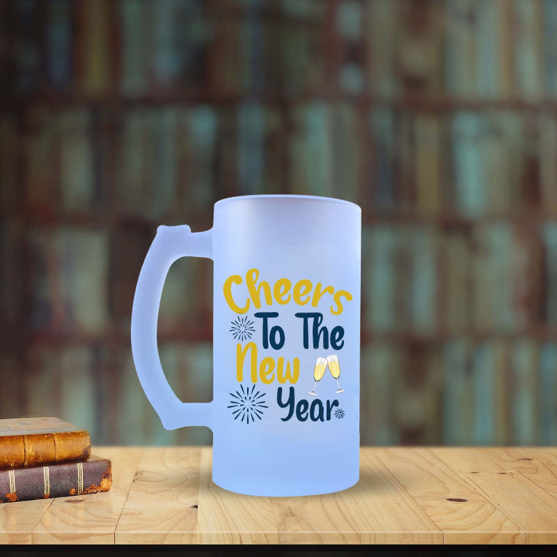 Frosted mug with 'Cheers To The New Year' text on a wooden table with a blurred bookshelf background
