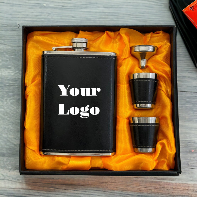 Black flask set with two cups and a funnel in a box on a wooden surface.