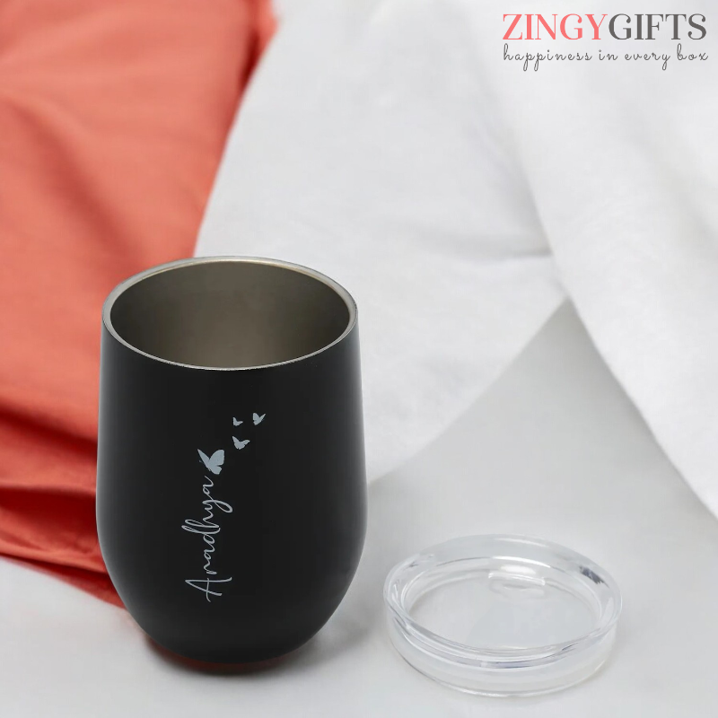 Black tumbler with engraved name and heart designs on a white surface, branded 'Zingy Gifts'.