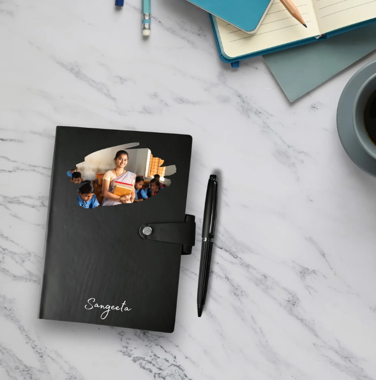 Black notebook with a photo cover on a marble surface with stationery items.