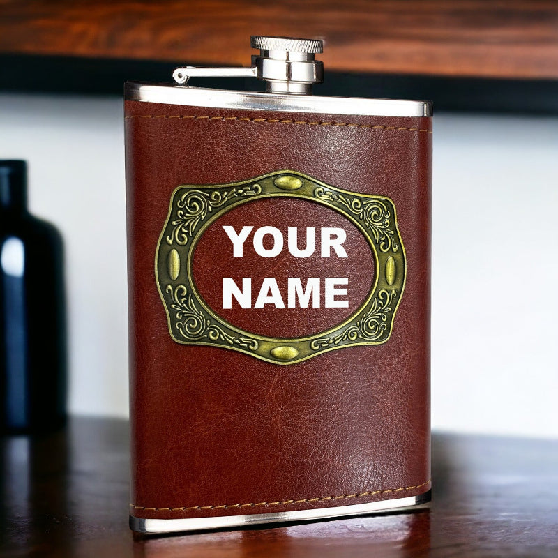 Brown leather flask with 'YOUR NAME' engraving on a wooden surface