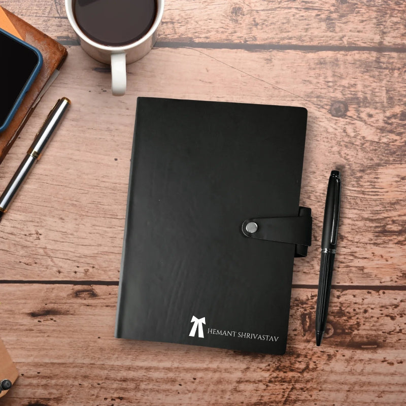 Black notebook with a pen and coffee cup on a wooden surface