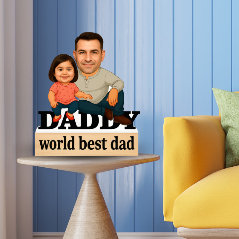 Decorative sign with a cartoon illustration of a man and child labeled 'Daddy world best dad' on a table against a blue wall.