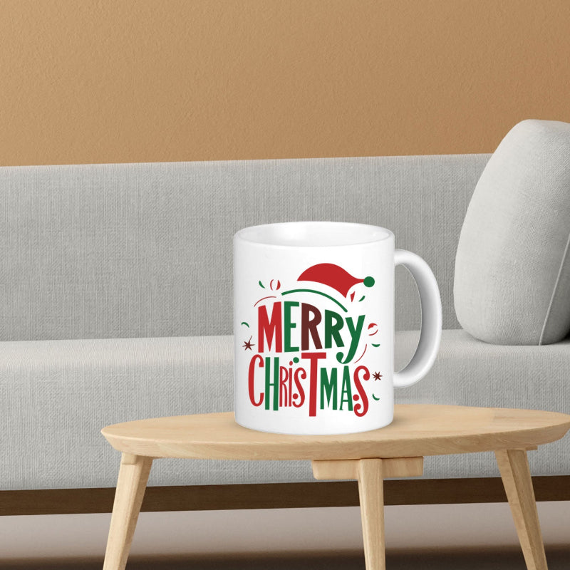 White mug with 'Merry Christmas' text on a wooden table against a beige wall.