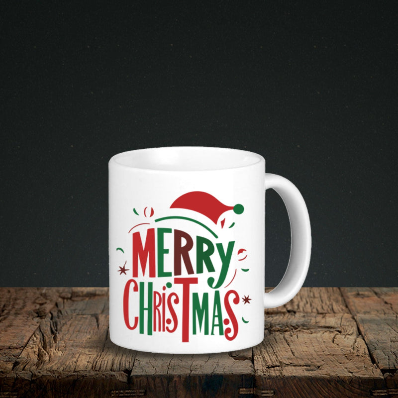 White mug with 'Merry Christmas' text and Santa hat design on a wooden surface.