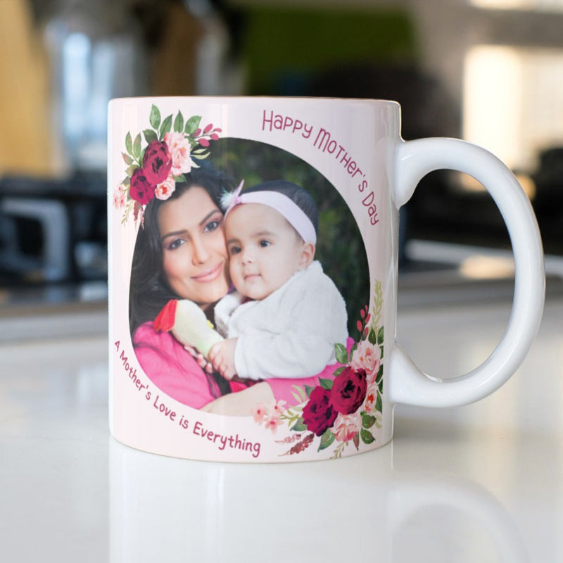 White mug with a photo of a woman and child, floral designs, and 'Happy Mother's Day' text on a blurred kitchen background.