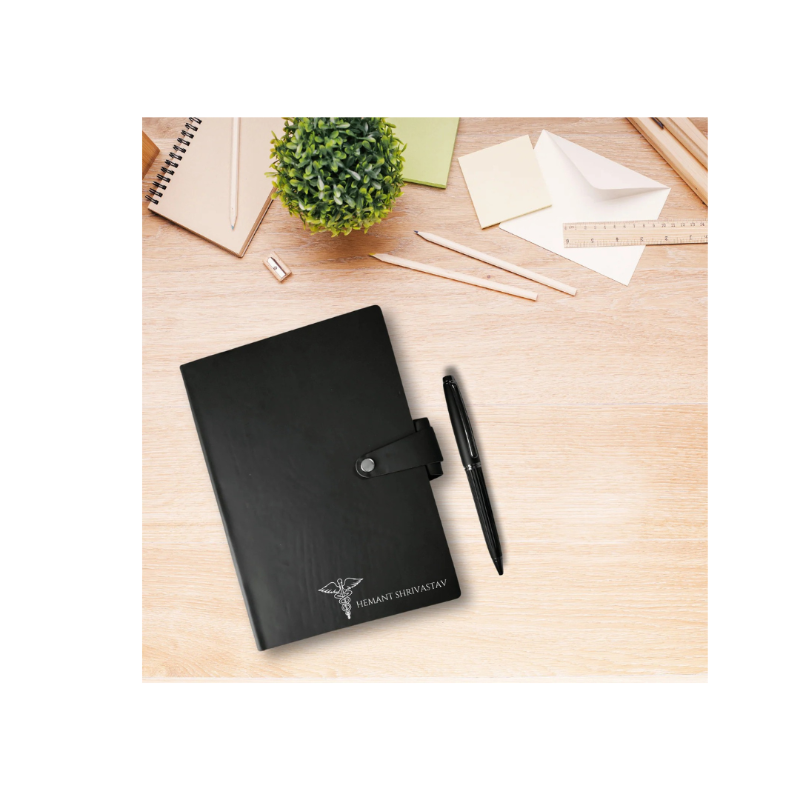 Black planner with a pen on a wooden desk with stationery items