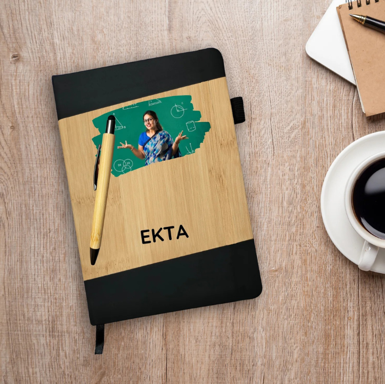 Notebook with wooden cover and black edges, featuring a photo of a woman and the name 'Ekta', on a wooden surface with a pen and coffee cup.