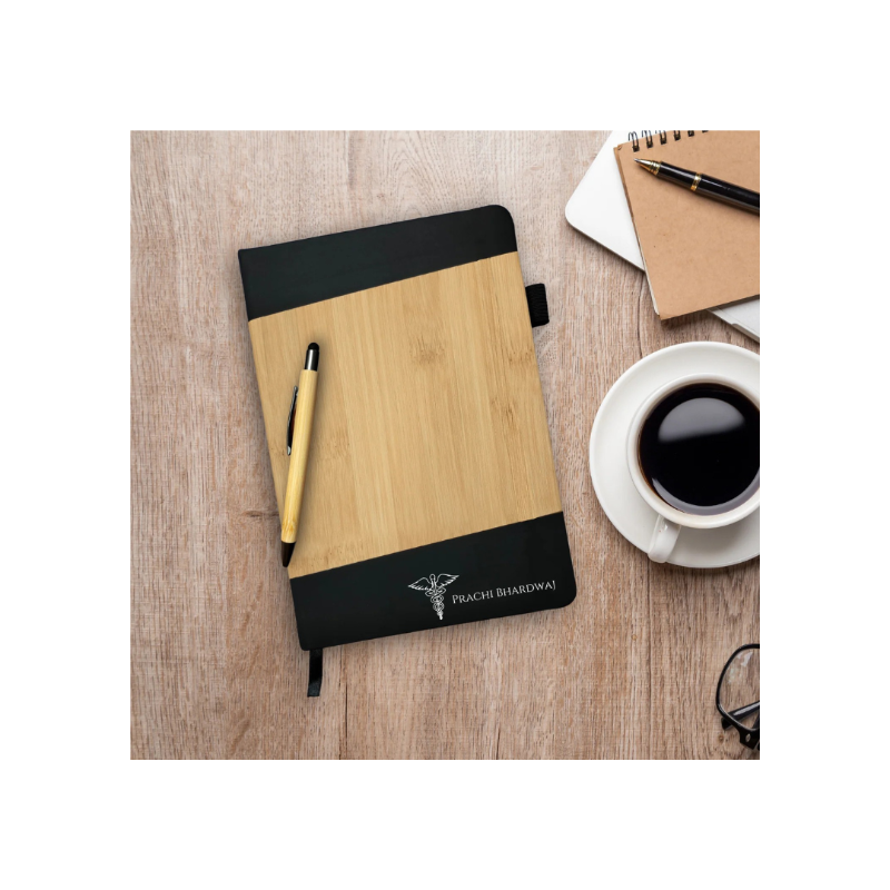 Wooden notebook with black cover on a wooden surface with a cup of coffee and pen.
