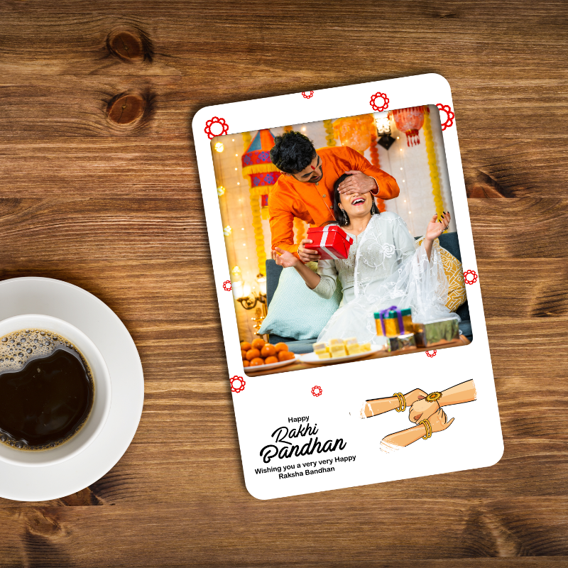 Card with a couple celebrating Dahi Handi on a wooden surface with a cup of coffee.
