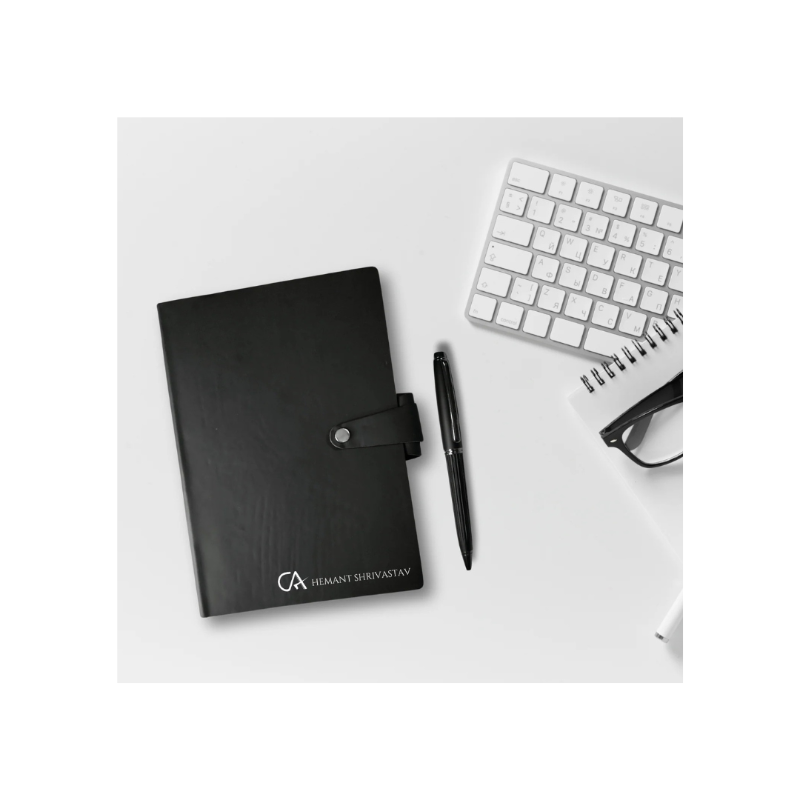 Black planner with a pen and glasses on a white surface