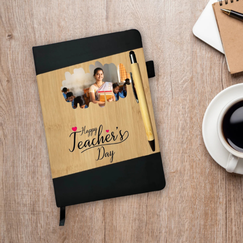 Notebook with 'Happy Teacher's Day' design on a wooden surface with a pen and coffee cup.