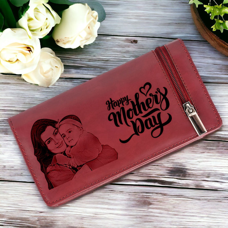 Red wallet with 'Happy Mother's Day' engraving and a母亲 holding child illustration on a wooden surface with white roses.