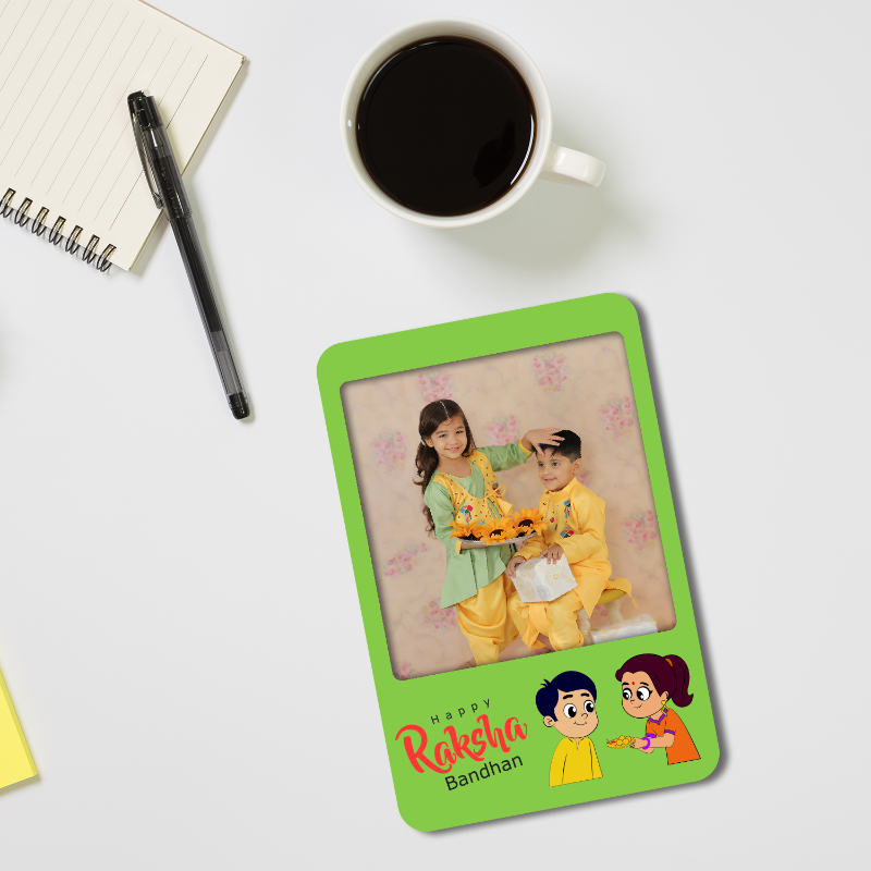 Green photo frame with a picture of two children on a white surface with a cup of coffee and notebook.