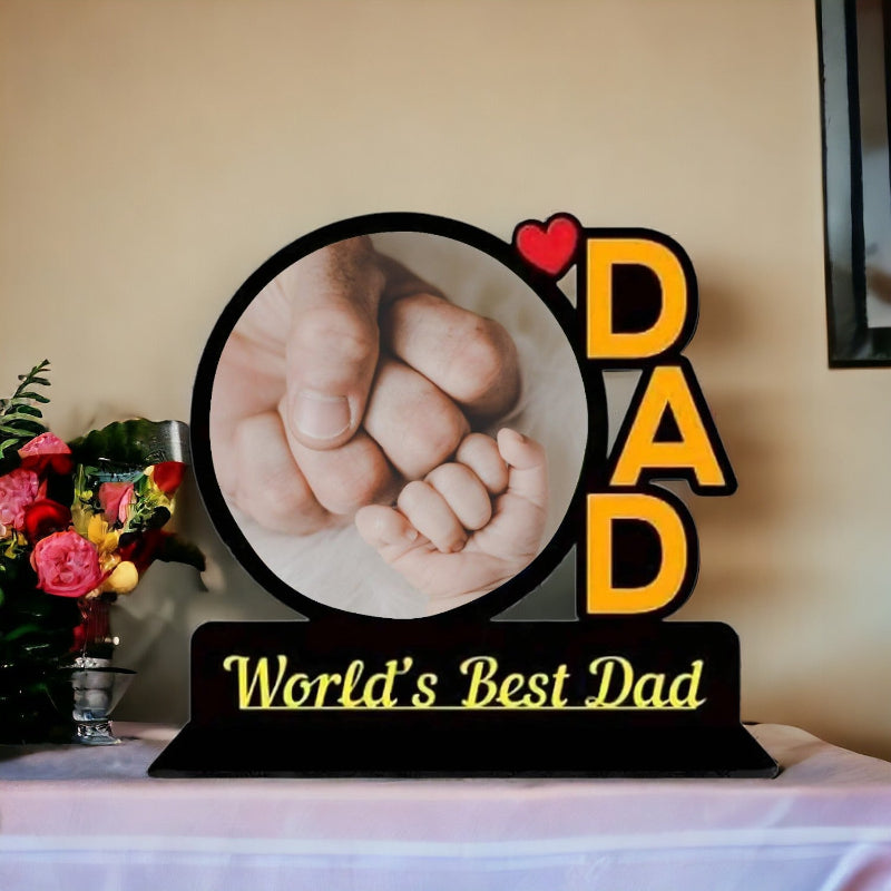 Decorative sign with a photo of two hands holding each other and 'World's Best Dad' text.