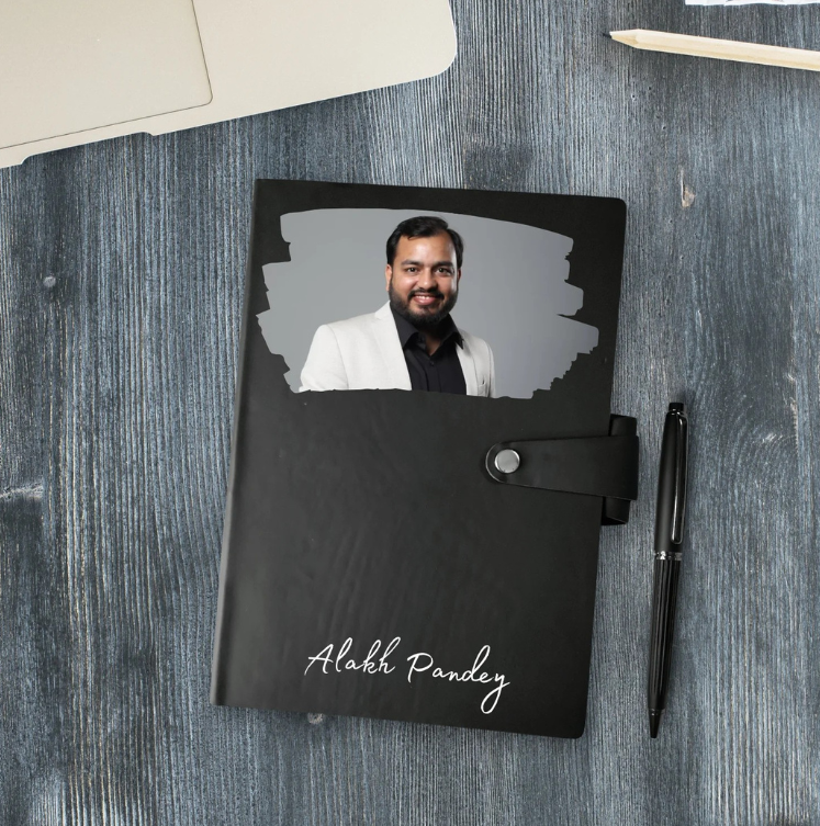 Black notebook with a photo of a man on the cover, placed on a wooden surface.