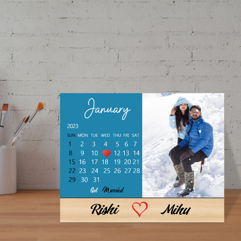 A custom desk acrylic calendar for 2022, personalized with photos, displayed on a desk with artistic brushes and a painting background.