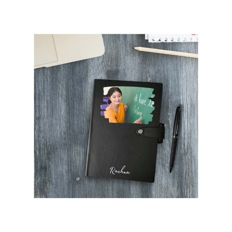 Black notebook with a photo of a woman on the cover, placed on a textured surface with a pen beside it.