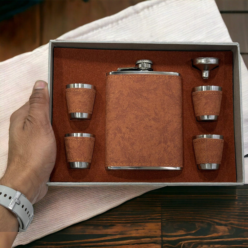 Brown leather flask set with four cups and a funnel in a box, held by a hand.