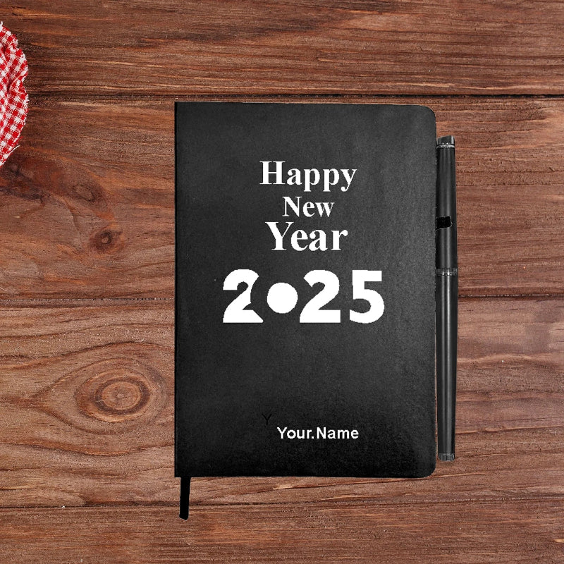 A personalized diary journal with 'Happy New Year 2025' printed on the cover, alongside a pen and a decorative object on a wooden surface.