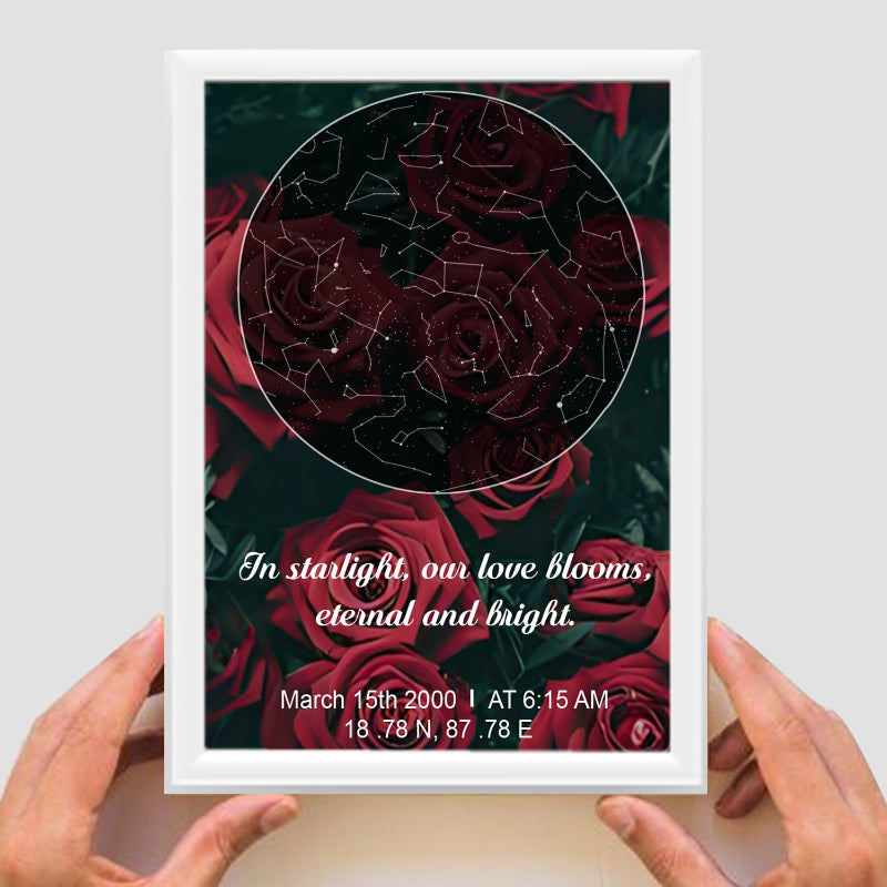 Framed artwork with red roses and star constellations, held by hands against a light gray background.
