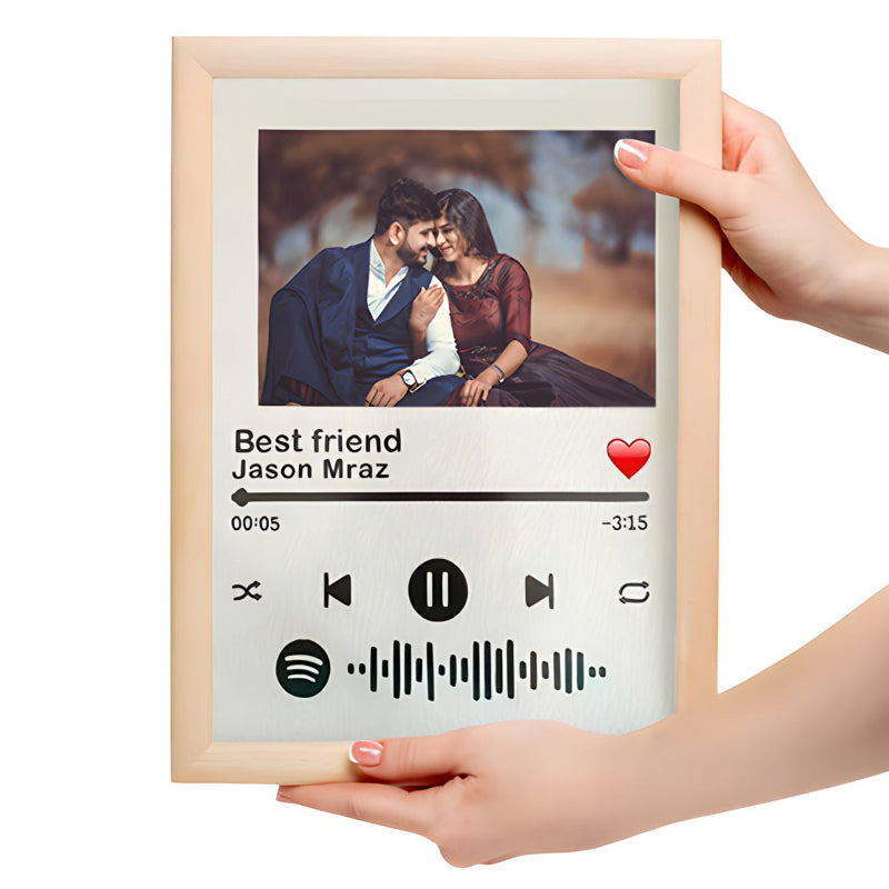 Framed photo of a couple with a music player interface overlay, held by two hands.