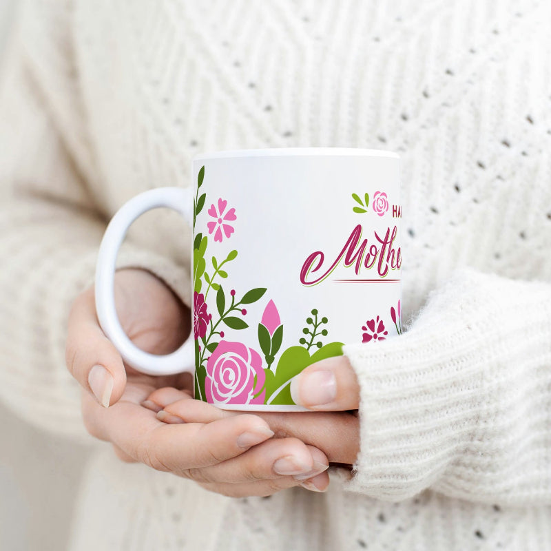 A person holding a white ceramic mug with colorful floral patterns and 'Sweet Mothers' text.
