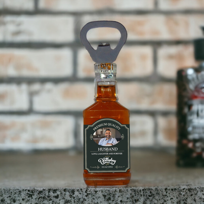 Bottle of whiskey with a custom label and bottle opener on a stone surface.