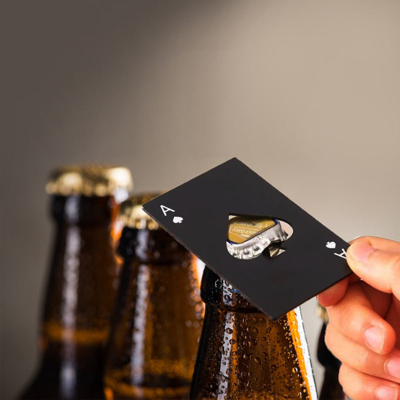 Playing card beer bottle opener being used on a beer bottle with blurred beer bottles in the background.