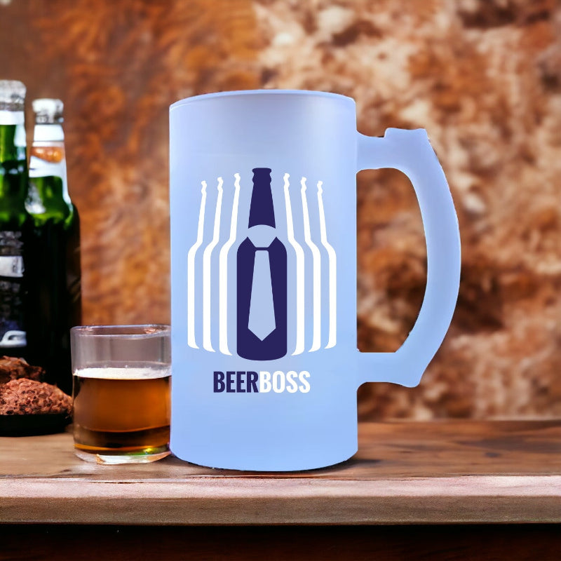 A blue glass beer mug with 'BEER BOSS' printed in a bold white text, accompanied by an illustration of a beer bottle and a tie, placed on a wooden surface with a blurred background.