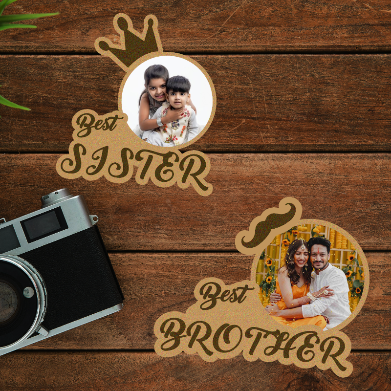 Two personalized fridge magnets with photos, one labeled 'Best Sister' and the other 'Best Brother', placed on a wooden surface next to a camera.